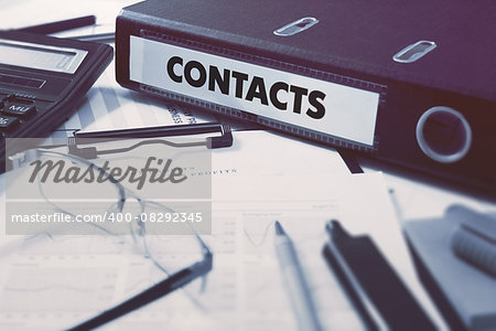 Contacts - Office Folder on Background of Working Table with Stationery, Glasses, Reports. Business Concept on Blurred Background. Toned Image.