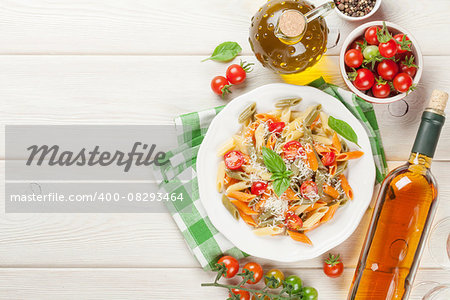 Colorful penne pasta and white wine on wooden table. Top view with copy space