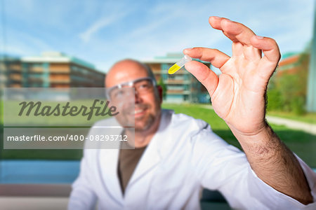 Chemist with safety goggles examining a yellow liquid