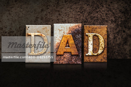 The word "DAD" written in rusty metal letterpress type on a dark textured grunge background.