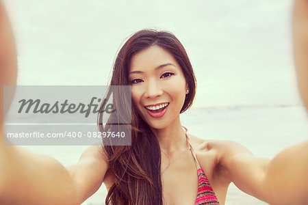 Instagram effect photograph of Asian young woman or girl in bikini, taking vacation selfie photograph at the beach