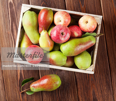 Pears and apples in wooden box on table. Top view