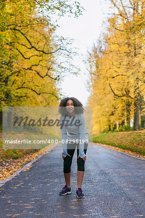 Beautiful mixed race African American girl teenager fitness running jogging in Autumn Fall trees