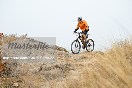 Cyclist in Orange Wear Riding Bike on the Beautiful Autumn Mountain Trail