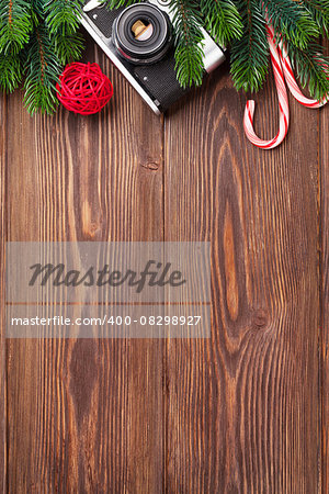 Christmas tree branch, camera and candy cane on wooden table. Top view with copy space
