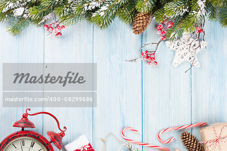 Christmas wooden background with snow fir tree, alarm clock and gift box. Top view with copy space