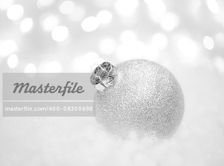 Christmas Decoration with White Ball in the Snow on the Blurred Background with Lights. Greeting Card with Space for Your Text
