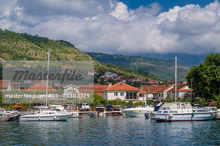 Small yacht marina with sailing boats landscape, mountain range and clouds background. Tivat, Montenegro
