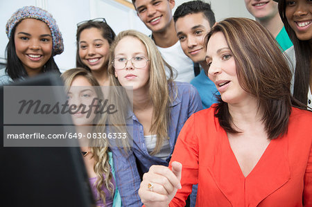 Female teacher explaining on computer to high school students