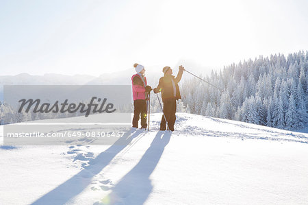 Senior couple on snow covered landscape holding walking poles looking away, Sattelbergalm, Tyrol, Austria