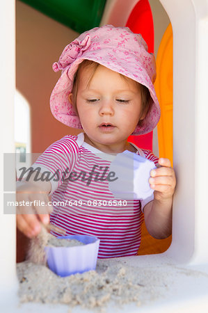 Female toddler playing with sand on playhouse windowsill