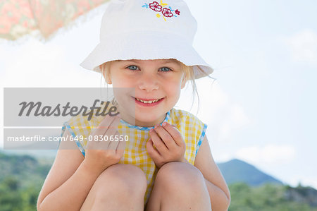 Girl wearing sunhat eating doughnut
