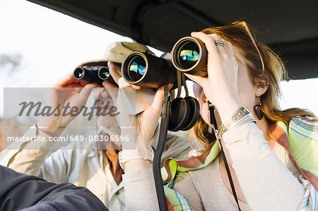 Senior man and daughter looking out through binoculars on safari, Kafue National Park, Zambia