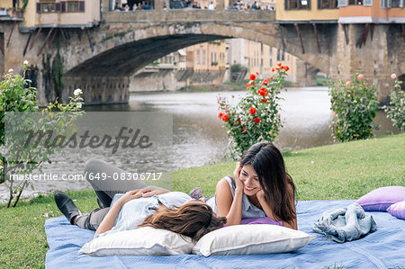 Lesbian couple lying on blanket in front of Ponte Vecchio over river Arno, Florence, Tuscany, Italy
