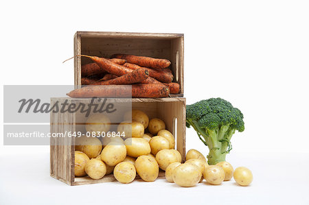 Wood crates filled with fresh carrots and potatoes and broccoli