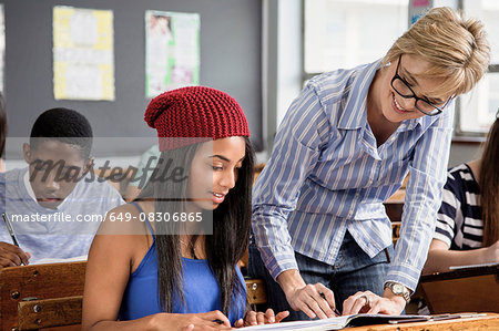 Teacher helping female student in classroom