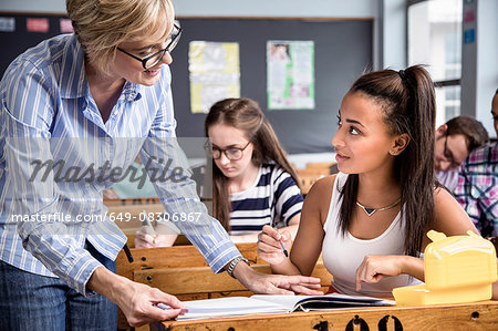 Teacher helping female student in classroom