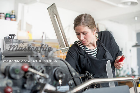 Female printer preparing print machine in workshop