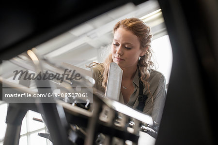 Female printer preparing paper for machine in workshop
