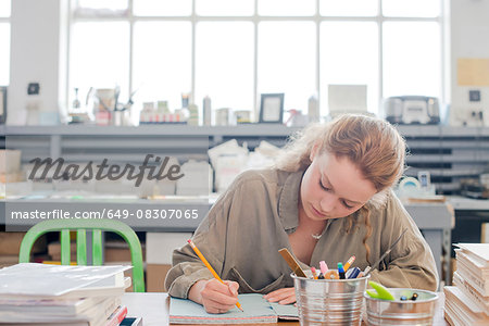 Female print designer working on sketchbook in workshop