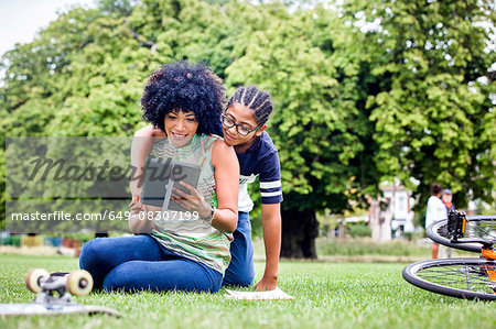 Boy and mother reading digital tablet together in park