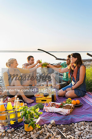 Friends sitting next to water haing a picnic making a toast, Schondorf, Ammersee, Bavaria, Germany