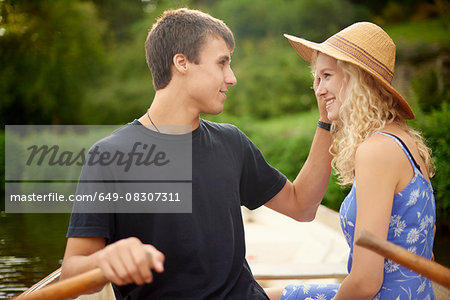 Romantic young couple rowing boat on rural river