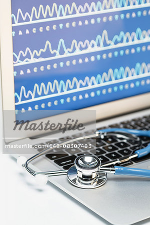 Medical genetics. Acoustic stethoscope on a laptop computer, that displays results of automated DNA sequencing