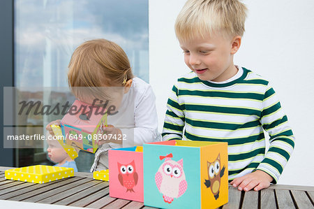 Boy and female toddler playing with owl building blocks on patio