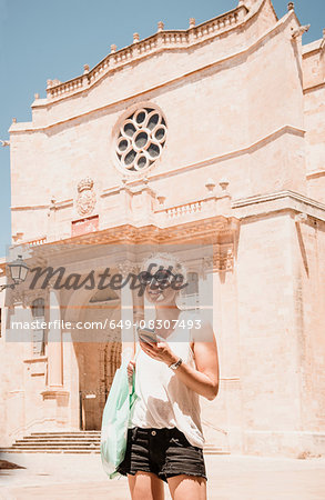 female tourist using smartphone in Ciutadella, Menorca, Spain