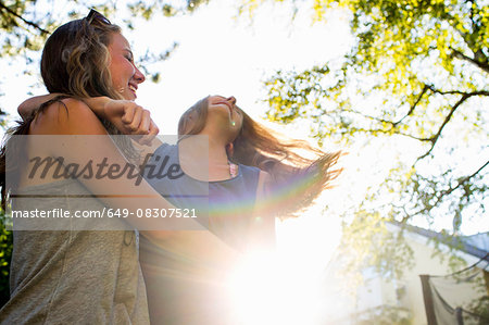 Two teenage girls dancing in sunlit park