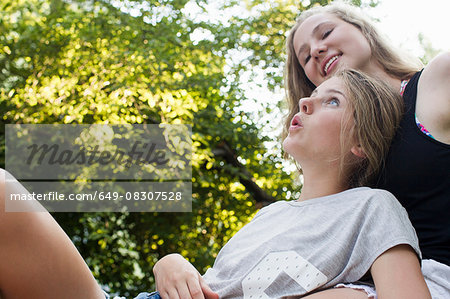Two teenage girls reclining in garden