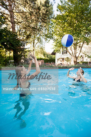 Two teenage girls playing with beach ball in swimming pool