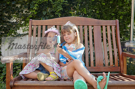 Girls enjoying ice lolly on garden bench