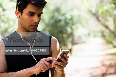 Jogger selecting music on smartphone in park