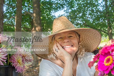 Portrait of senior female farmer wearing sun hat with cut flowers