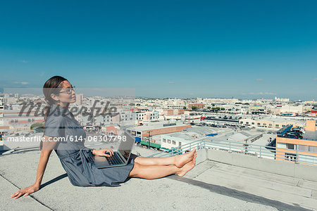 Businesswoman using laptop on roof terrace, Los Angeles, California, USA