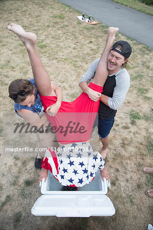 Two young men dunking friend into cooler on Independence Day, USA