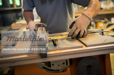 Wood artist in workshop, using woodworking machinery, mid section