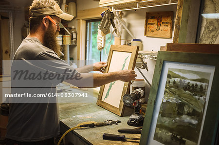 Artist working in workshop, framing artwork