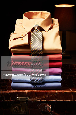 Stack of shirts with ties on suitcase in studio