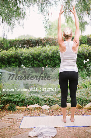 Blond woman doing yoga in a garden.