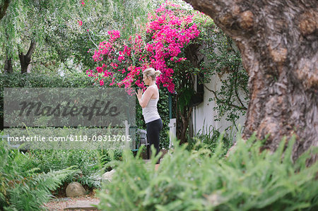 Blond woman doing yoga in a garden.