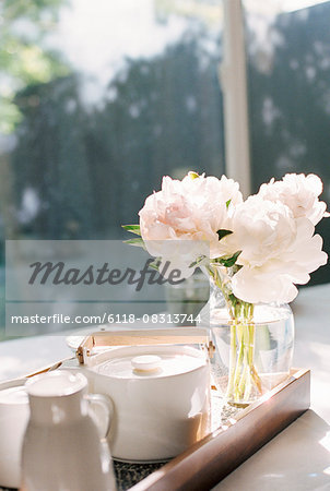 Tray with a teapot and a vase with white roses.