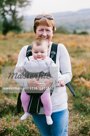 A woman carrying a baby in a baby carrier, on an autumn walk.