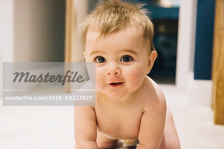 A young baby crawling on a rug.