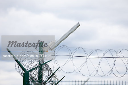 Wired fence with rolled barbed wires on white background