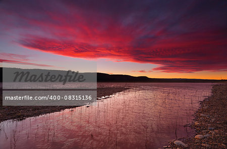 Brisk and windy winter sunset sky and reflections over Lake Burralow in Penrith, Australia