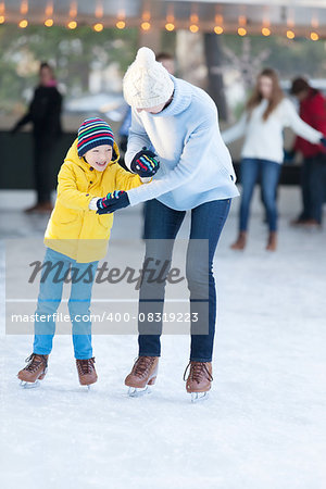 family of two enjoying winter time ice skating together at outdoor skating rink