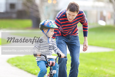 young father teaching his son to ride the bike in the park